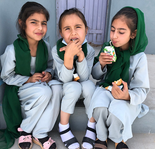 Afghan girls eating the school provided snacks at lunch.