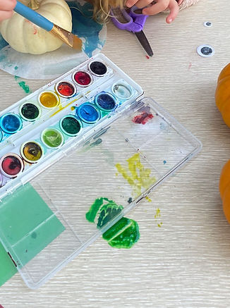 Children's watercolor paints and small orange pumpkins