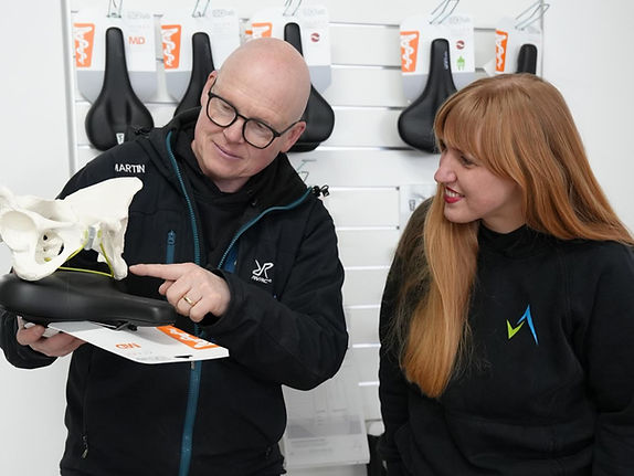 Person links erklärt wie das Becken auf dem Fahrradsattel sitzt und woher Schmerzen und Taubheitsgefühle beim Fahrradfahren kommen