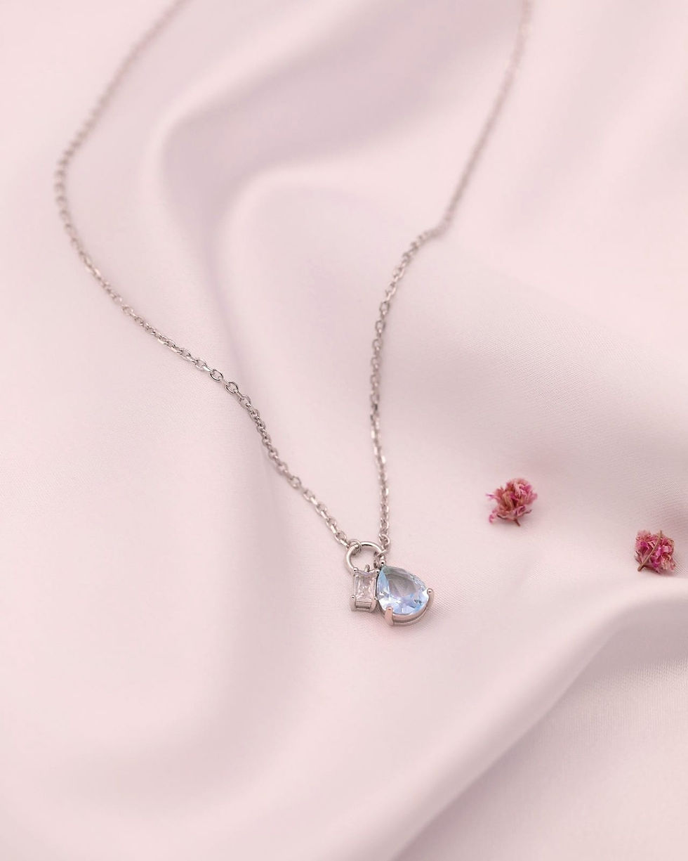 Miniatura: Fio em prata pendente - duas pedras lapidadas, sobre fundo cetim branco.