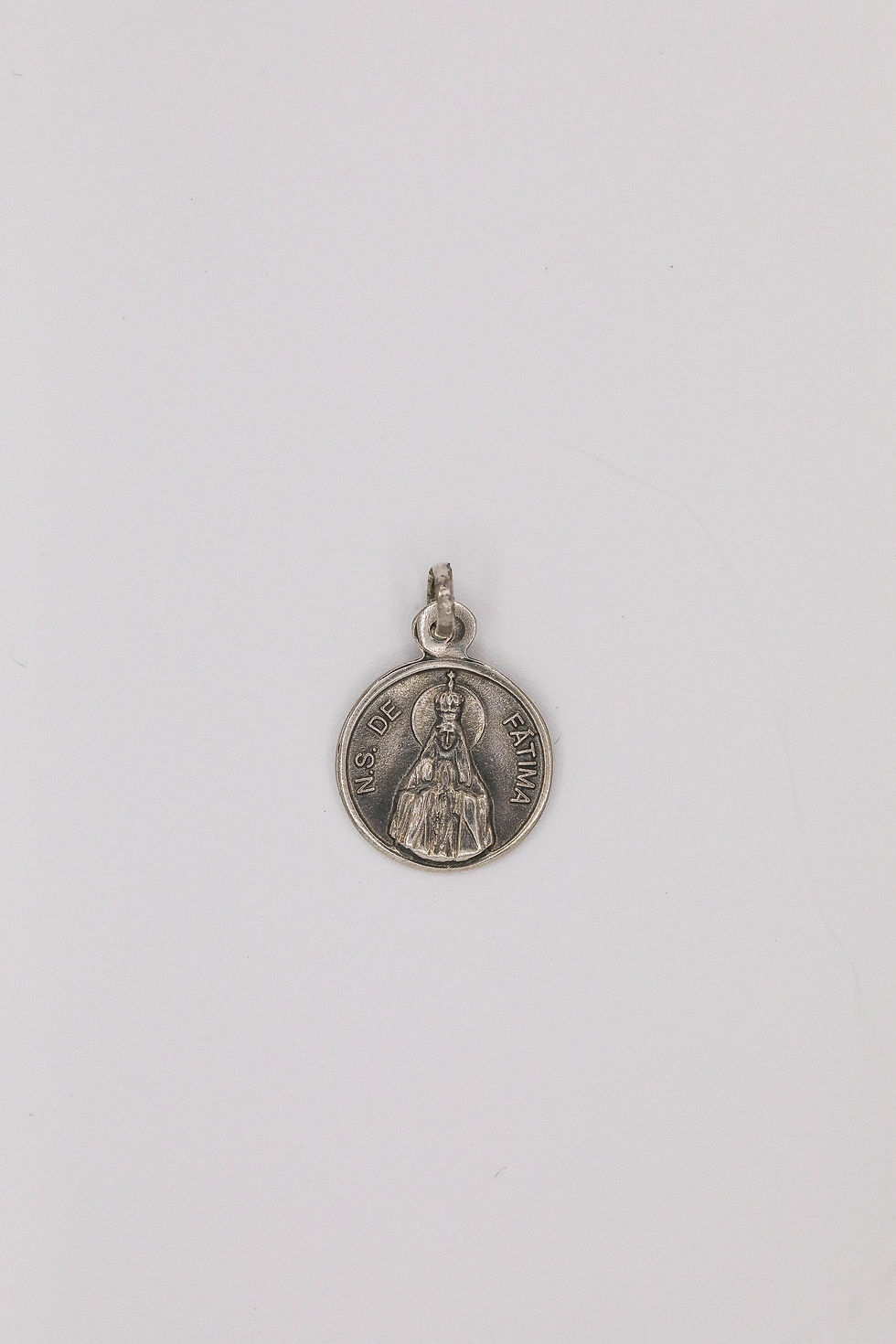 Medalha redonda, em prata, de Nossa senhora de Fátima.