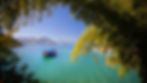 Foto do mar de angra dos reis, entre arvores e com um barco colorido no meio