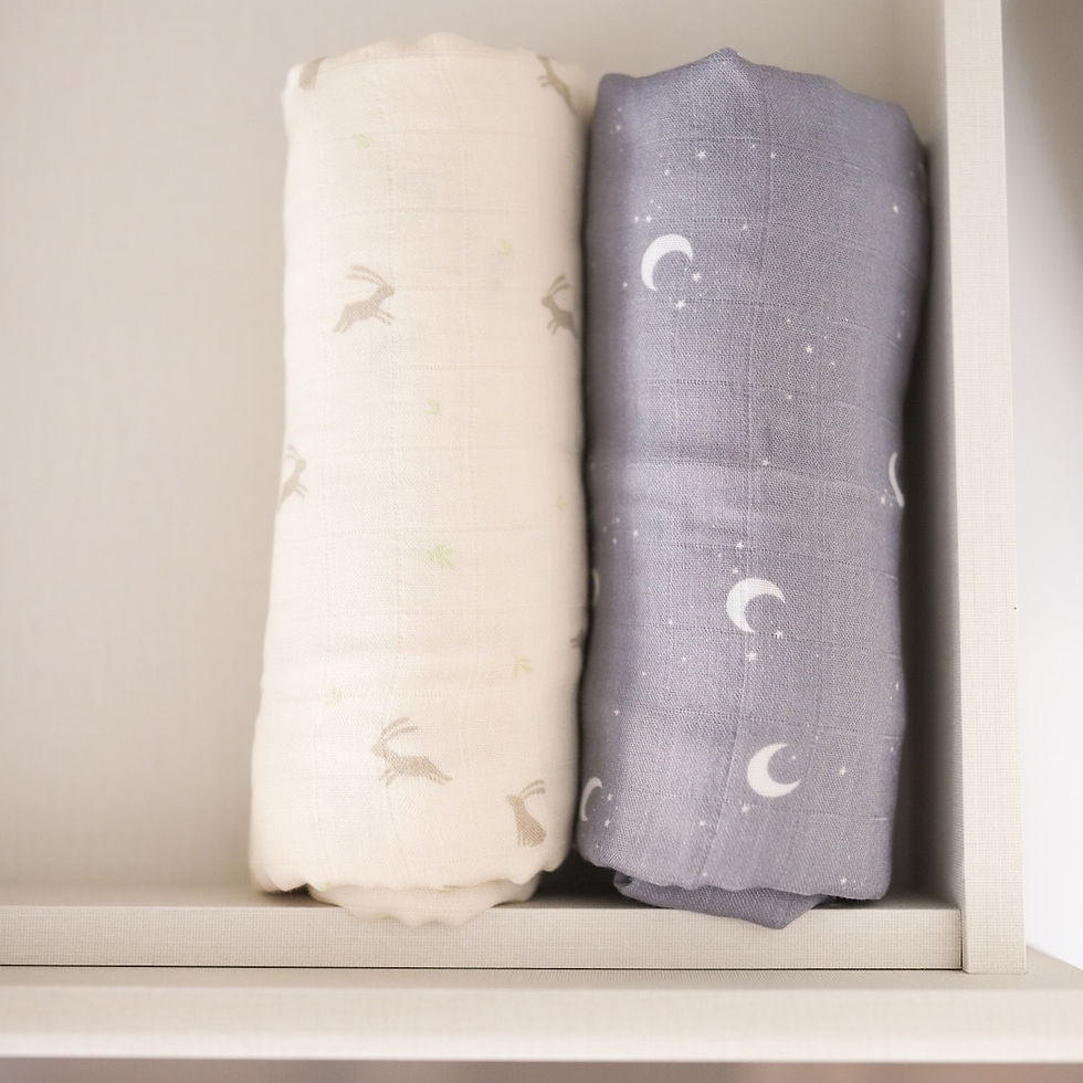 Thumbnail: Mellow baby swaddle Luna in grey with white moons paired with a cream swaddle adorned with green motifs, displayed together