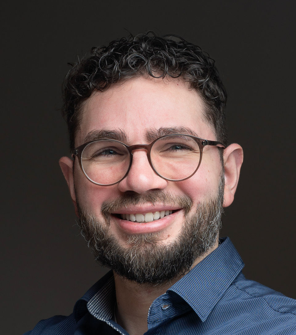 Portrait professionnel d'un homme souriant, lunettes, barbe, logo photographe.