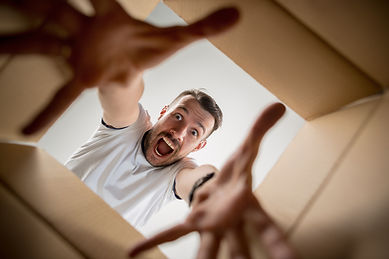 The surprised man unpacking, opening carton box and looking inside. The package, delivery,