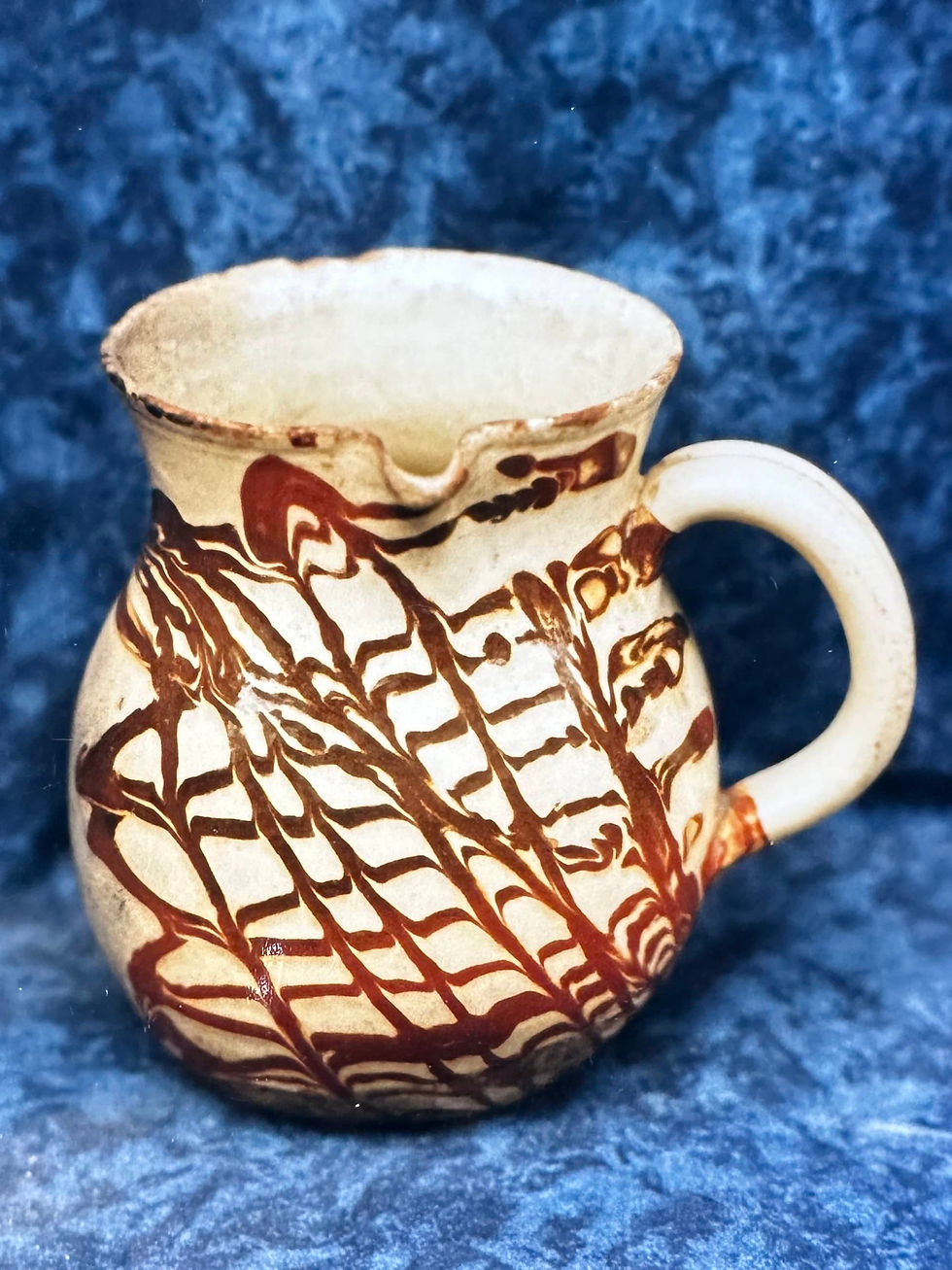 Pichet ventru à anse verticale et col évasé, décoré sur fond blanc-crème de motifs en croisillons  bruns avec des taches rouges