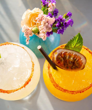 Photographic Shot from the top of two Margaritas cocktails on a table of the Restaurant Taco Paco in Ibiza. Next to them you can see a little vase with a bunch of flowers.