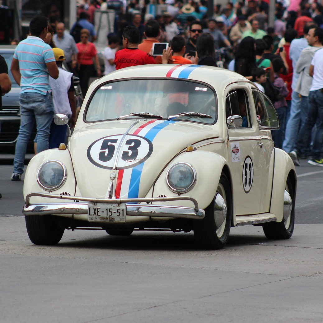 Weißer VW Käfer Rennwagen Herbie mit der Startnummer 53 auf einer Straße.