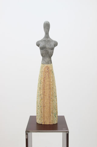 Female body modeled in concrete with a dress made from a homemade wood pulp, alternately modeled with acrylic paint. Mounted on a steel base.