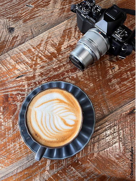 a coffee and a camera on a brown wooden table 