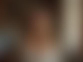 Vrouw glimlacht ontspannen en kijkt vriendelijk in zacht daglicht, symbool voor wel-zijn en tevredenheid.