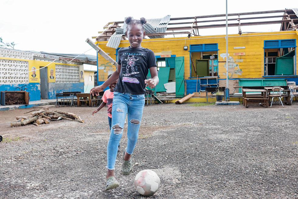 Children play football in the courtyard of their damaged school. Ferris Cross, Westmoreland