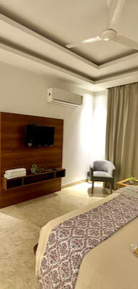 Boutique hotel room with modern TV, AC, bed, and stylish decor.