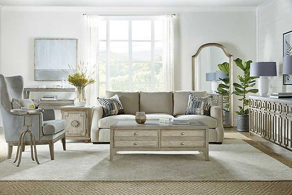 A photograph of a biege sofa, chair, cocktail table, end table and console in a sunny white room.