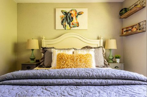country bedroom with cow picture over bed