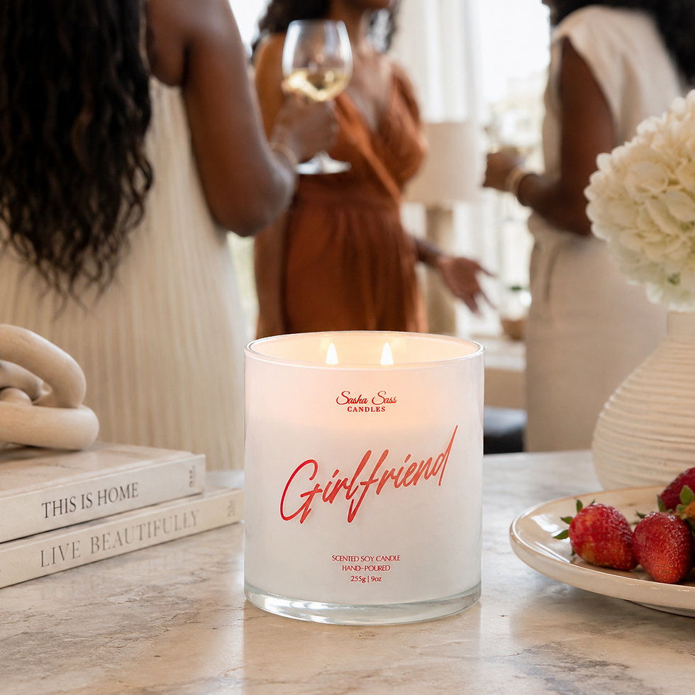 Women standing around drinking with a lit Girlfriend soy candle on table and a plate of strawberries