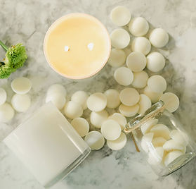 White glass candle jars on counter with wax melts laying next to them.