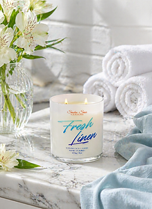 Fresh Linen soy candle in white glass jar beside folded white towels and white flowers