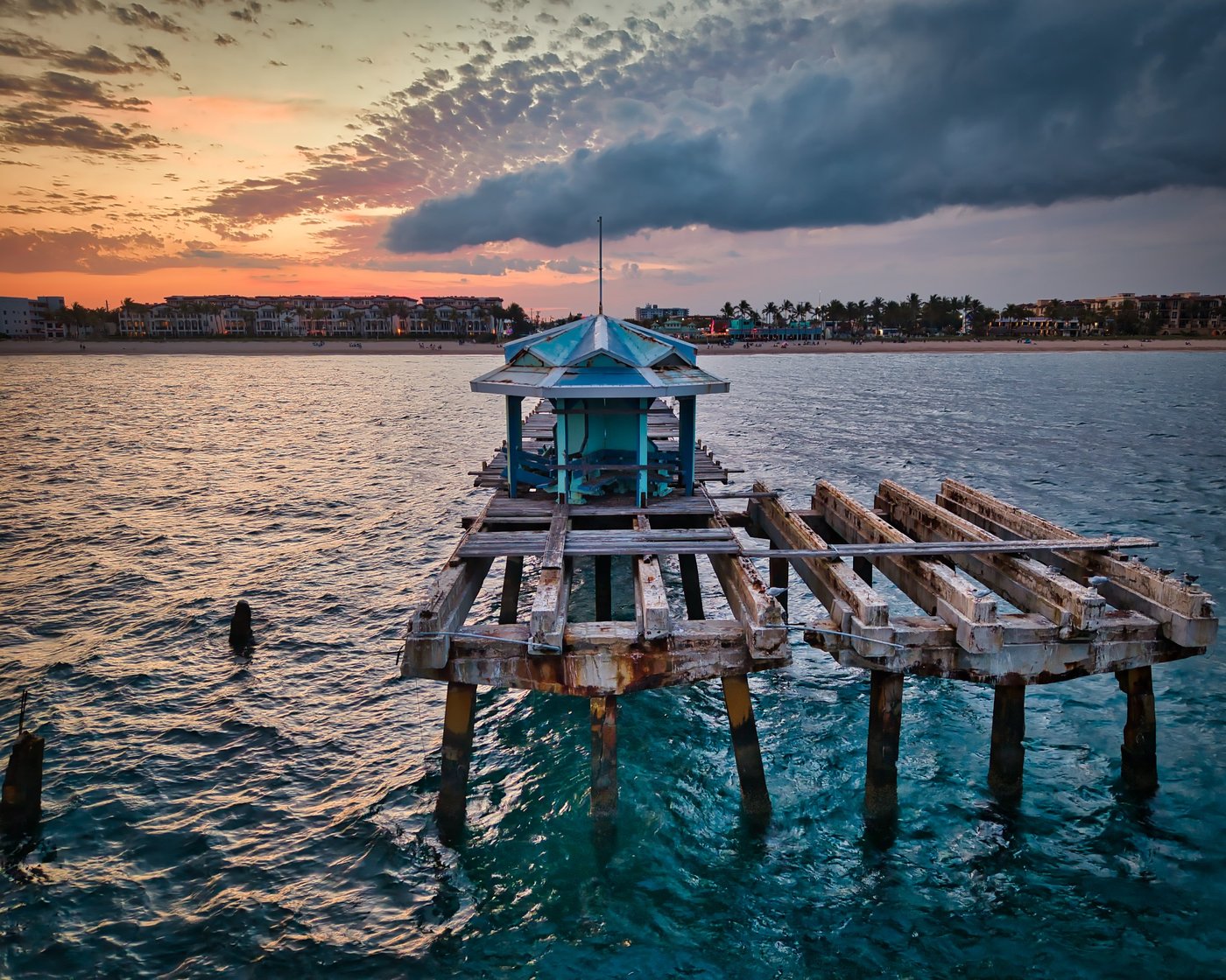 Blue-roofed shelter on a weathered wooden platform over water.