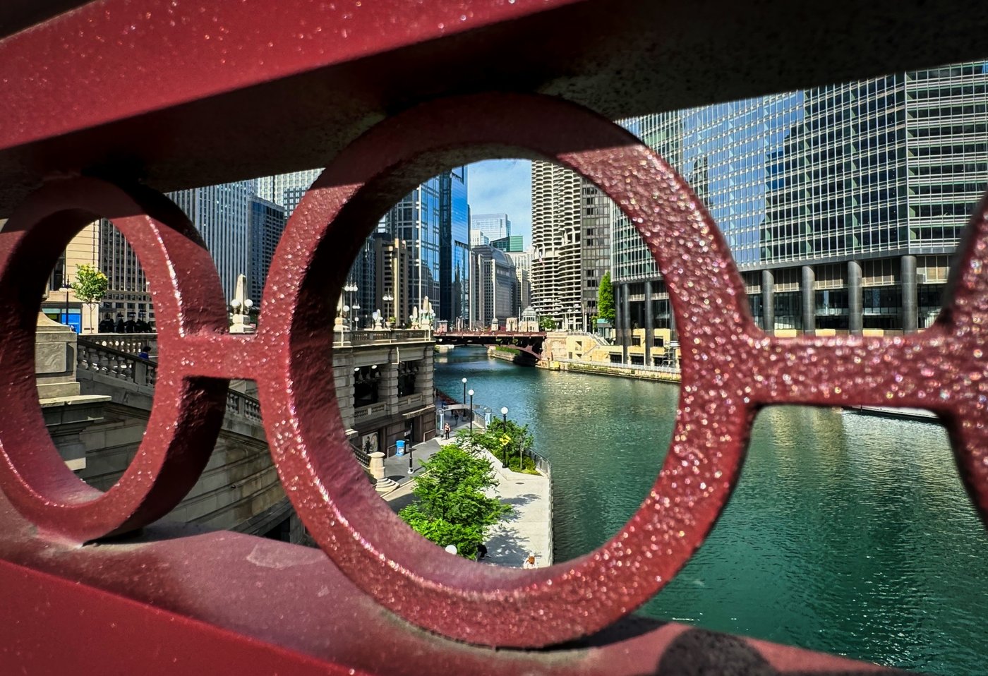 Cityscape Through the Rails Chicago River and skyscrapers seen through circular openings in a red bridge railing.