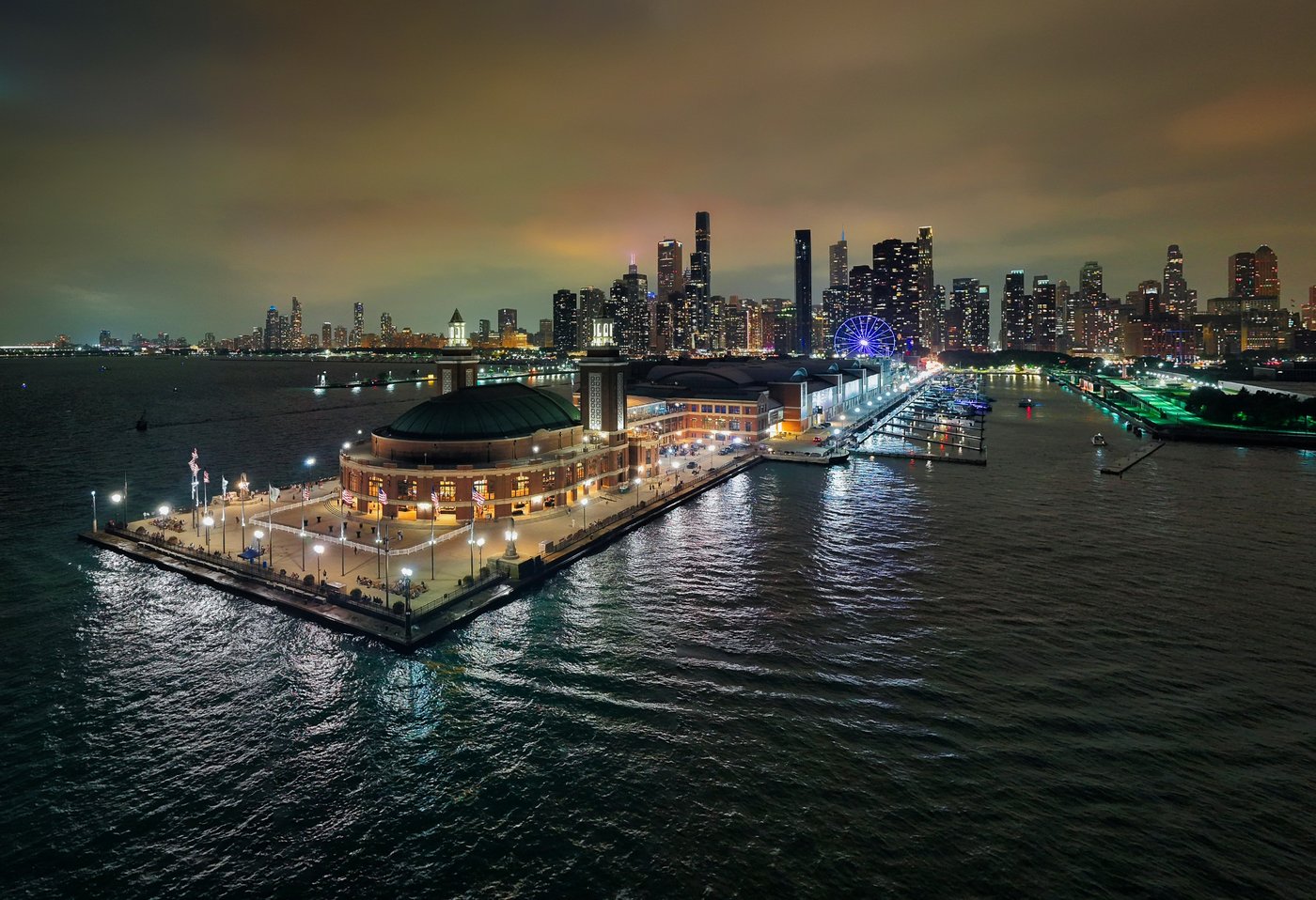 Navy Pier, City Beyond Navy Pier pavilion and walkway illuminated at night with the Chicago skyline beyond.