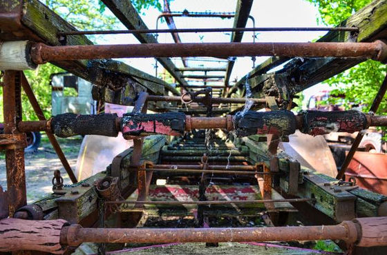 Rusted mechanical framework and pipes viewed along a series of crossbars.