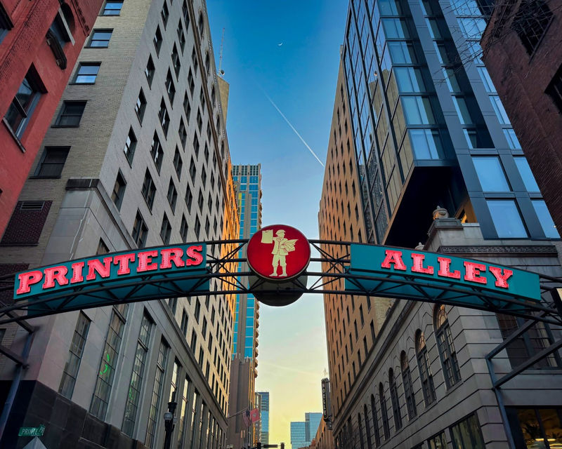 Printers Alley sign spanning a narrow passage between tall buildings.