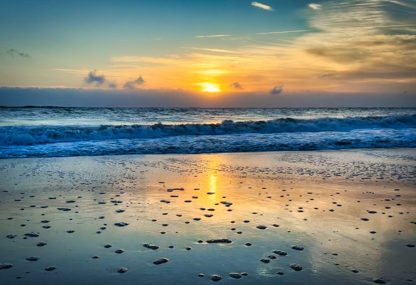 Gold Across the Wash Low sun over ocean waves reflected on wet sand.