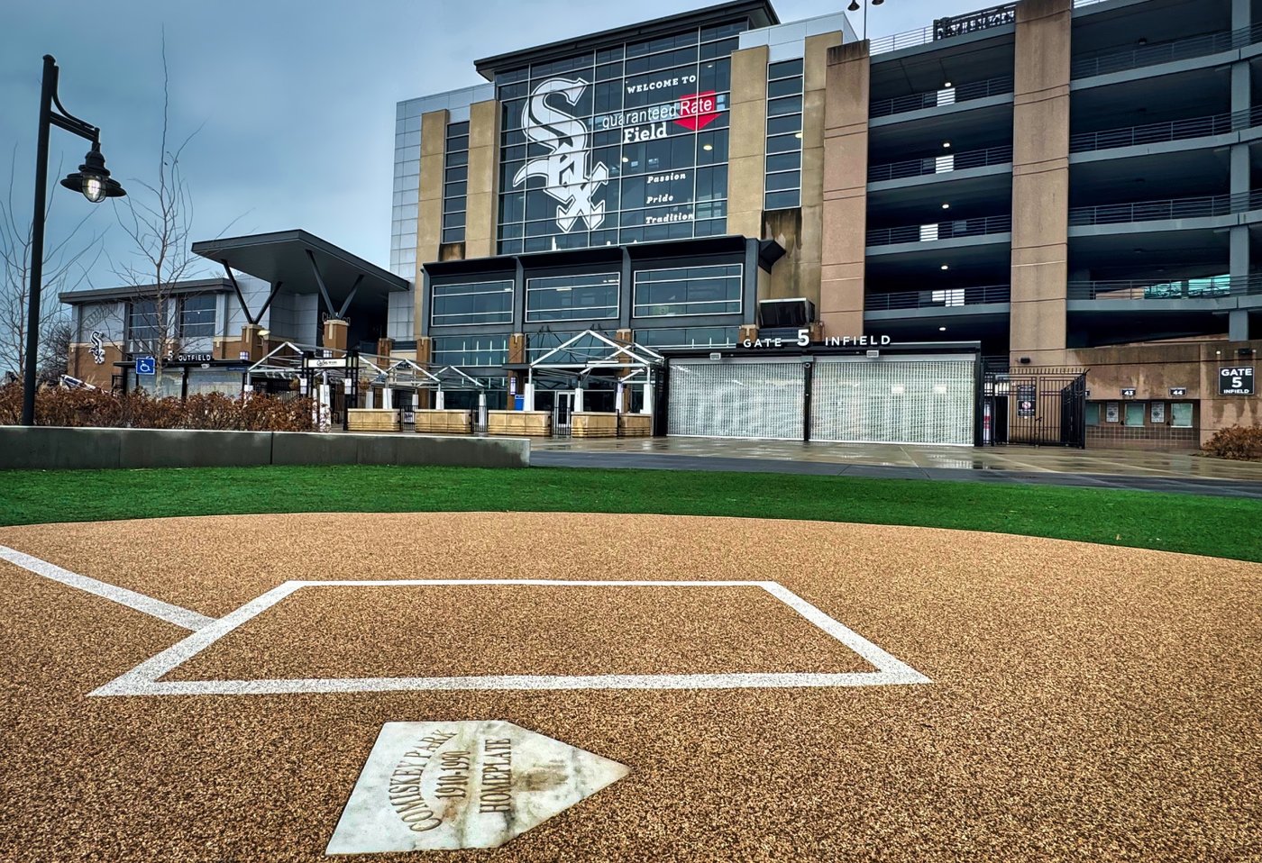 Home Plate to History Home plate markings in front of a stadium displaying the White Sox emblem.
