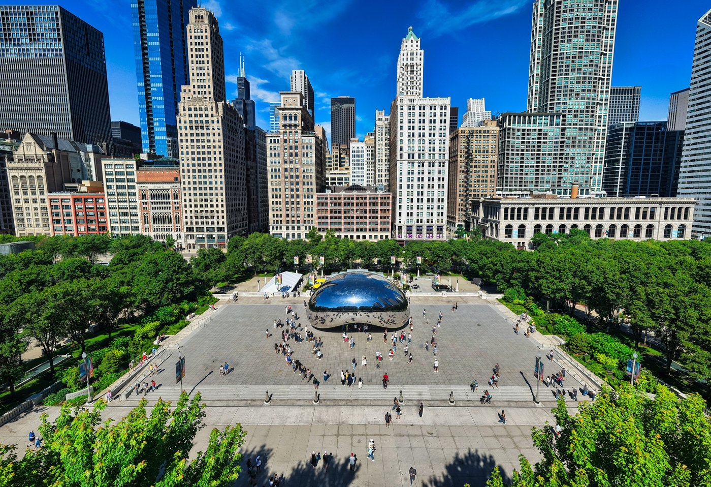 Millennium in the Mirror Aerial view of Cloud Gate in Millennium Park with surrounding plaza, trees, and buildings.