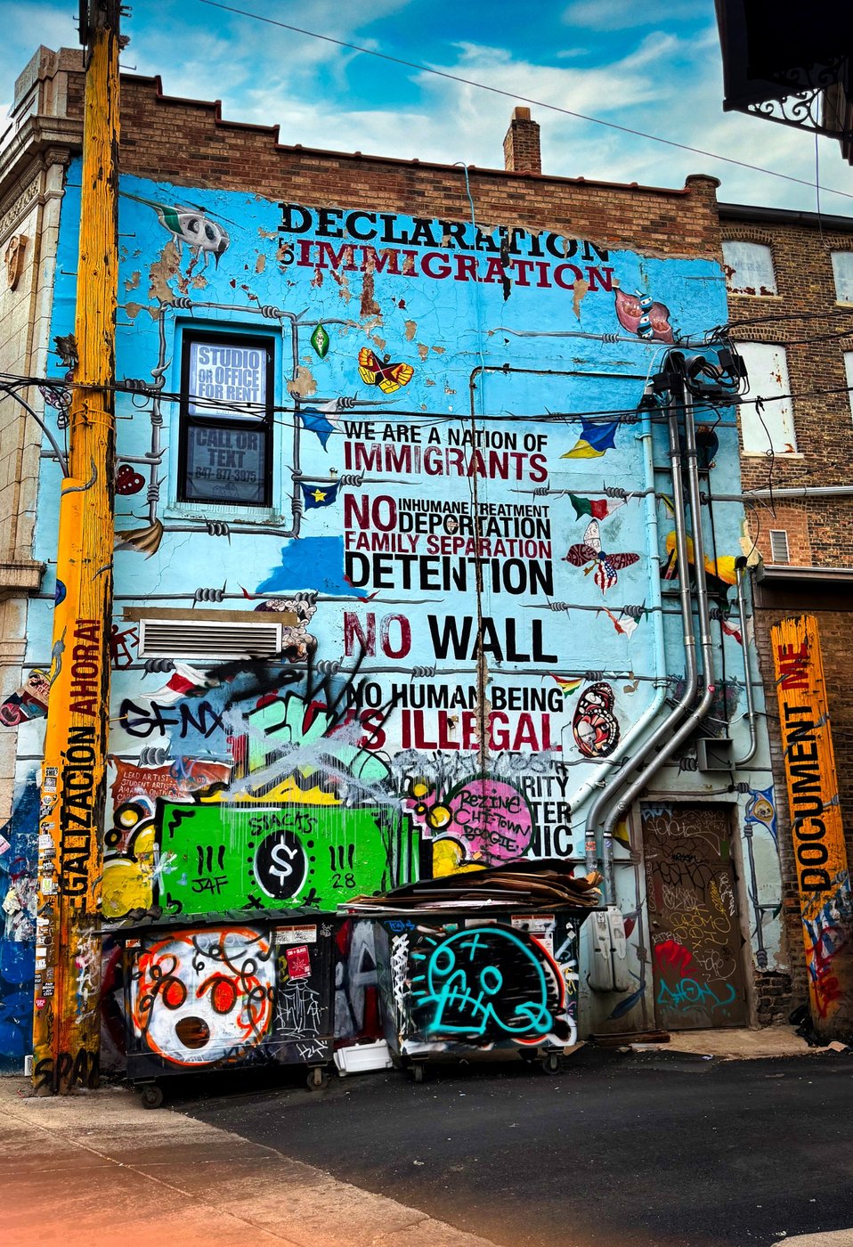 Voices on the Corner Colorful Chicago building facade covered with immigration-related lettering, murals, and stickers.