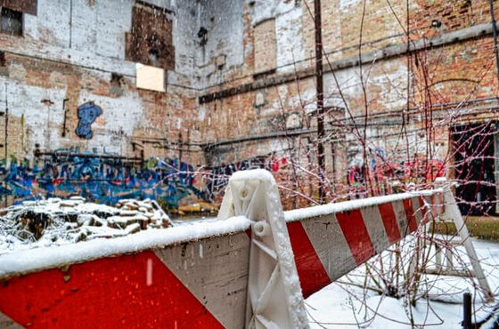 Snow-covered red and white barrier inside a graffiti-marked brick ruin.