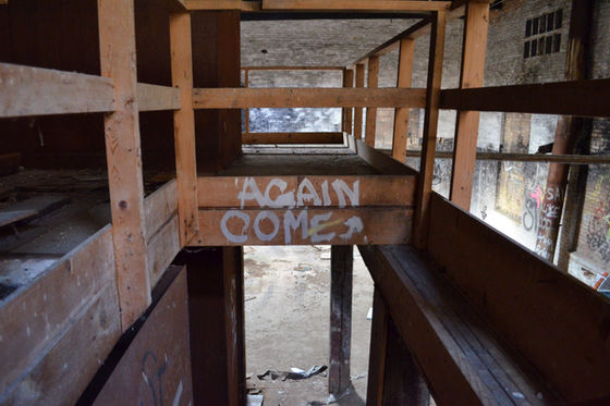 Wooden railings and graffiti above an interior stair opening.