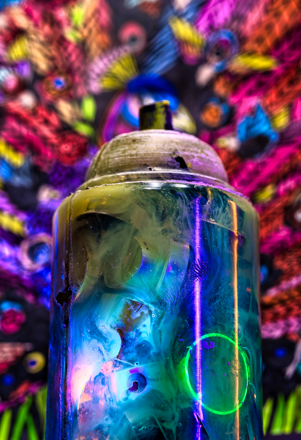 Paint-covered aerosol can before a brightly colored patterned background.