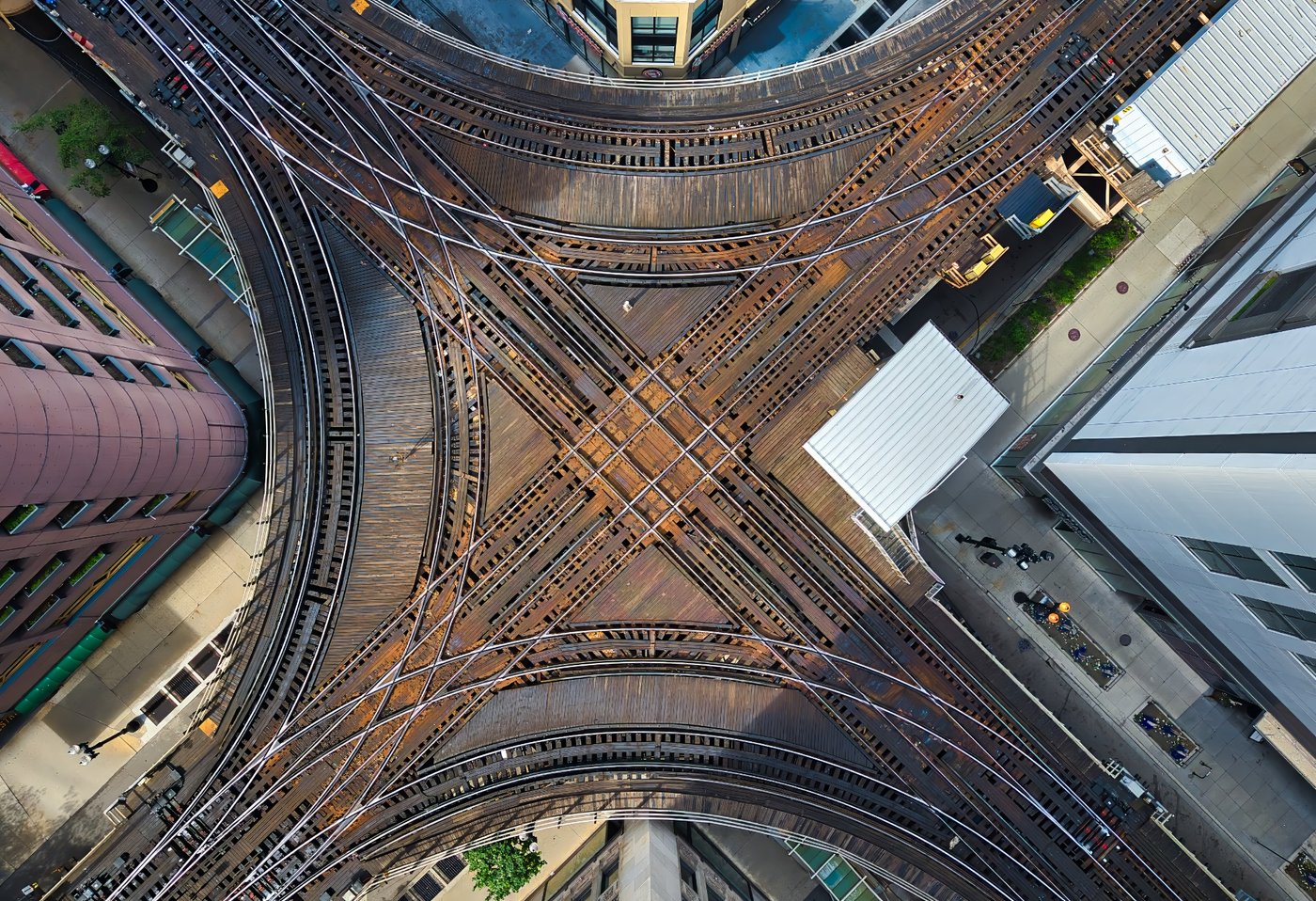 Where the Rails Cross Direct overhead view of intersecting elevated railway tracks between Chicago buildings.