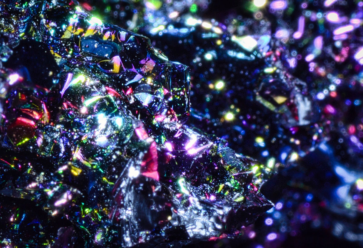 Dark reflective crystal facets scattered with multicolored highlights.