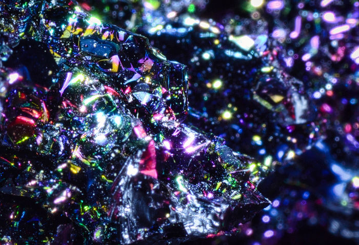 Dark reflective crystal facets scattered with multicolored highlights.