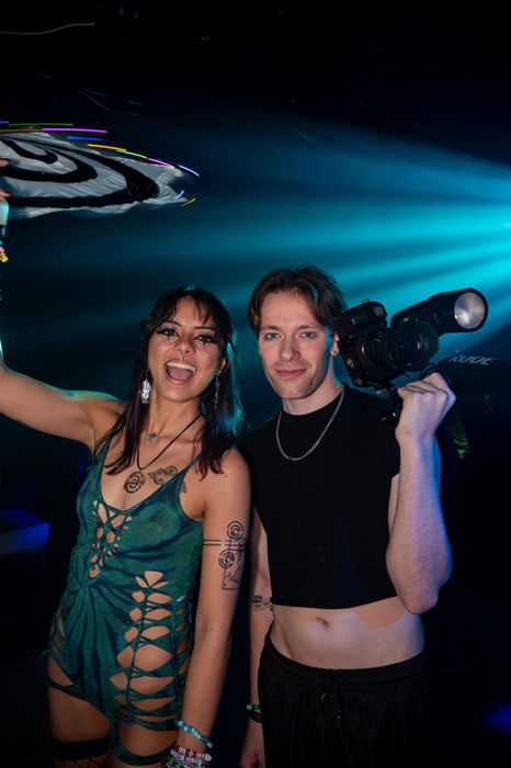 Smiling woman in green outfit, man with camera at an event