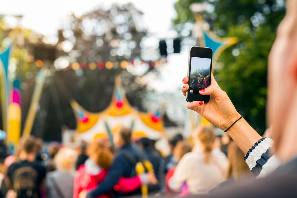 Hand holding phone recording outdoor festival crowd