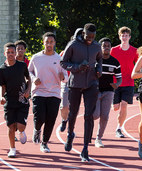 Peter Bol running with a group of young athletes