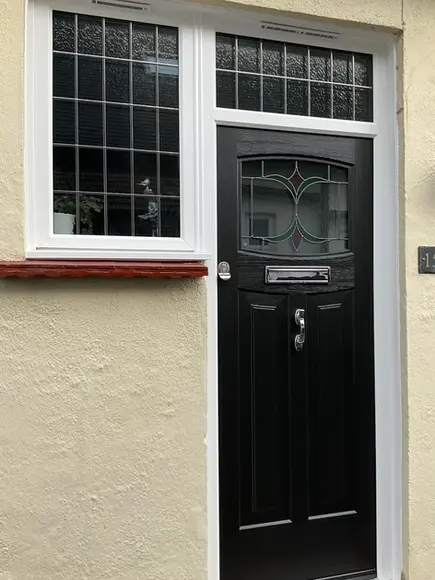 Black front door with decorative glass and house number