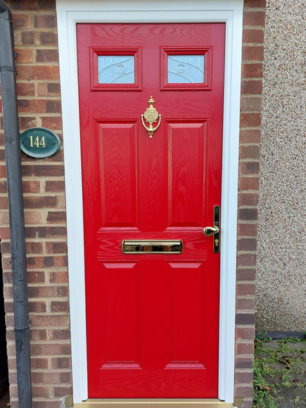 Bright red traditional front door with brass furniture