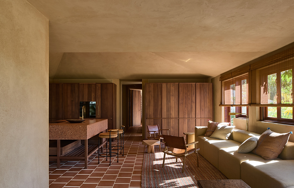 Cozy room with brown wood cabinets, terracotta tile floor, beige sectional sofa, and sunlight streaming through blinds. Modern and warm.