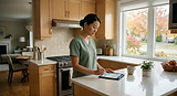 A Verdant Care Partners caregiver logging visit notes on a tablet in a client's kitchen