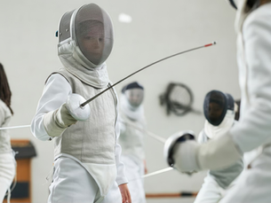 Children training in fencing masks and jackets during a beginner fencing class