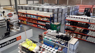 Sky view of a roofbase branch. Shelves stocked with roofing products and a man is near the counter