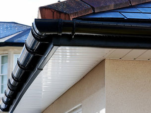 Image of black roof guttering on a white gravel house
