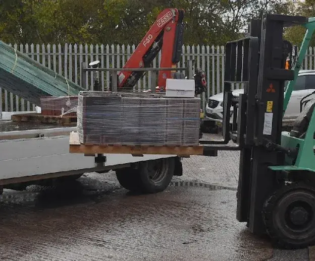 Two Roofbase Exeter workers outside. One of them in a forklift machine picking up tiles.
