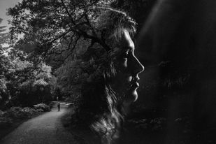 Double exposure of the silhouette of a woman in a black and white forest trail