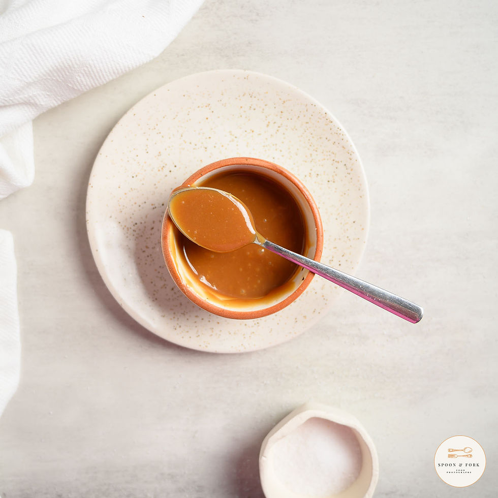 A portion of homemade salted caramel in a pot with some sea salt next to it in a dish
